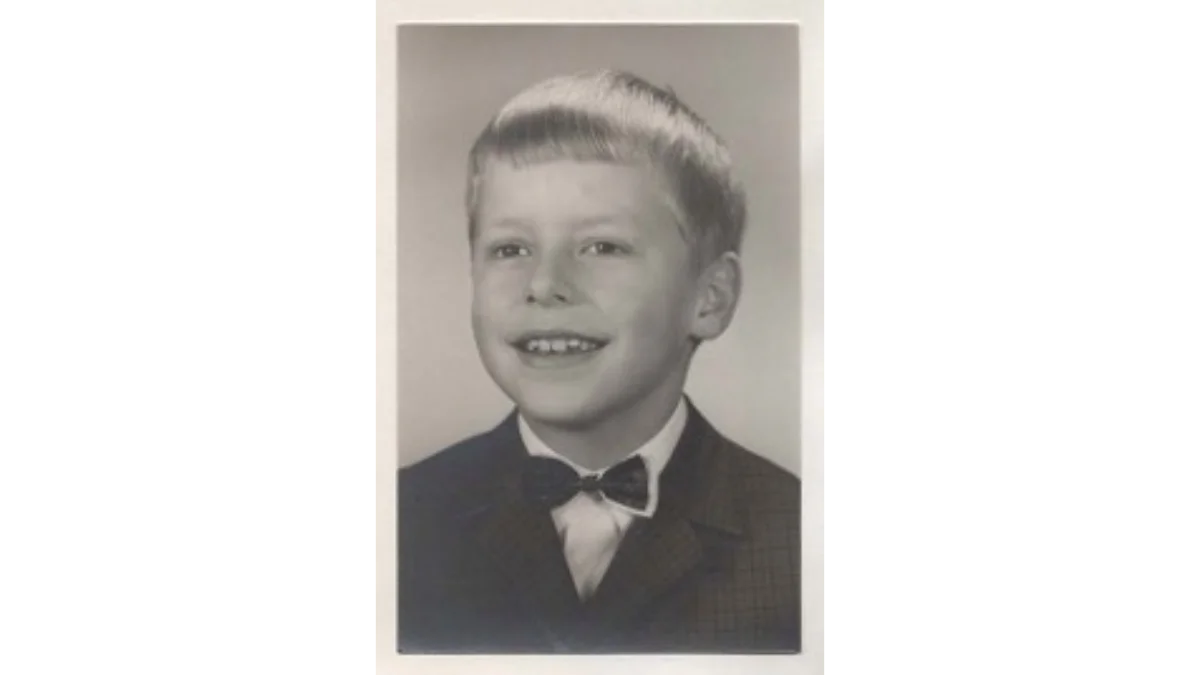 Ein historisches Schwarz-Weiß-Porträt des jungen Klaas Theo, der freundlich mit einer Fliege in die Kamera lächelt; sein früher Tod bildet den Kern des Kindheitstraumas des Autors.